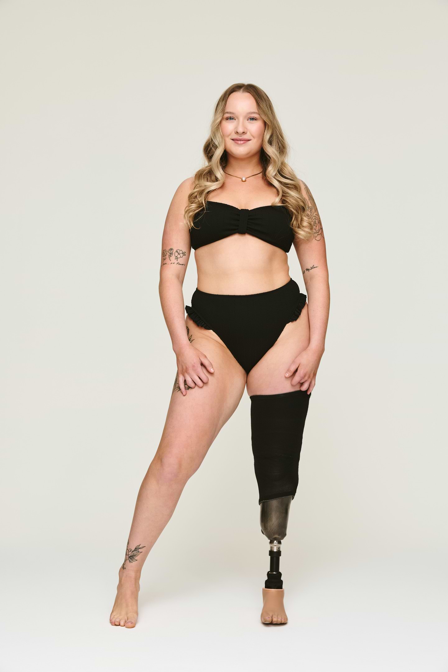Chloe Hofman wearing a black swimsuit and standing confidently with a prosthetic leg