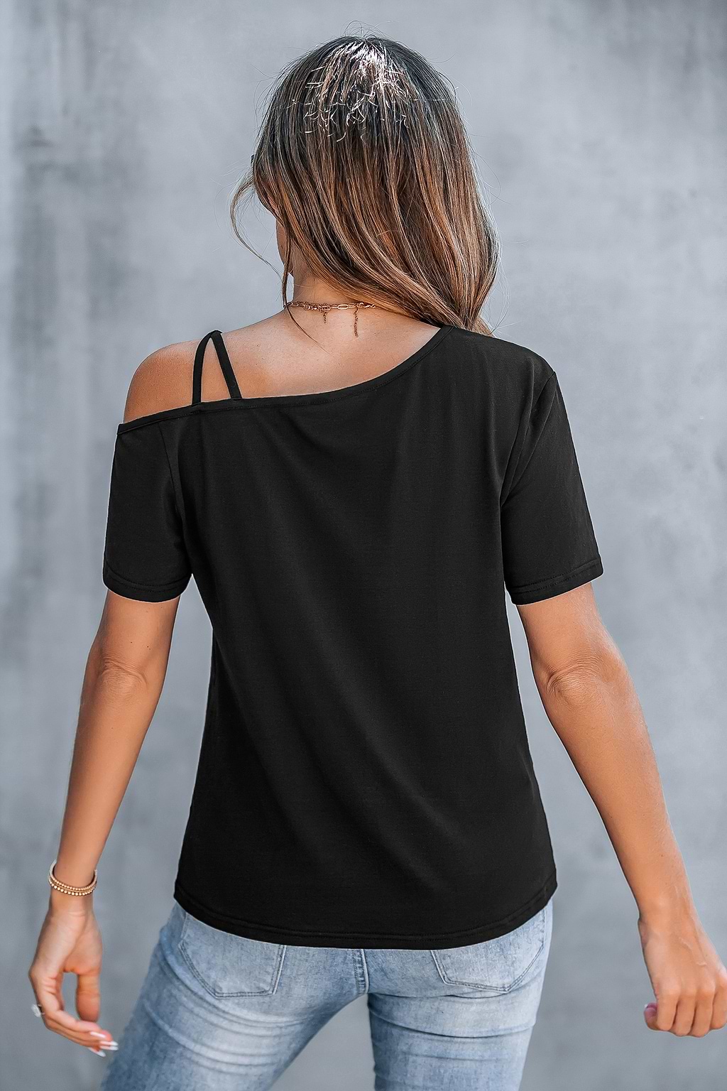 Camiseta negra con corte asimétrico y hombros retorcidos